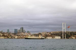 Istanbul, tacchino - dicembre 28, 2022. degno di nota passeggeri nave andare in barca su il bosphorus stretto passaggio sotto il ponte a tramonto. foto