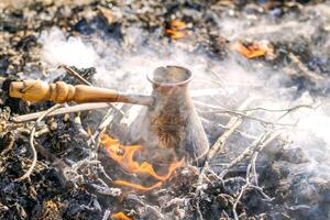 bollente caffè nel Turco cezva su fuoco di bivacco carboni. foto