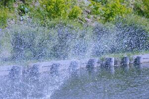 bellissimo gocce di acqua spruzzi a partire dal un' Fontana su un' estate soleggiato giorno. foto