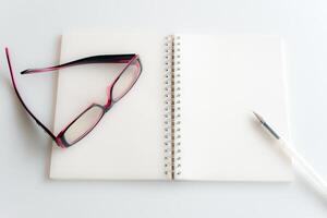 pagina bianca di un taccuino e occhiali da vista foto