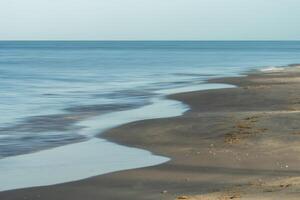 il spiaggia con movimento onda e spazio foto