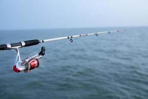 canna da pesca e mulinello da spinning e sfondo di acqua di mare foto