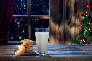 vista ravvicinata di un bicchiere di latte con biscotti sul retro del colore