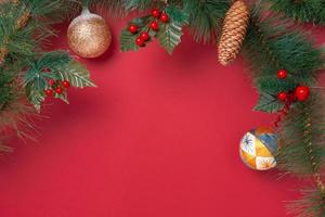 decorazione natalizia e ghirlanda di rami di abete con ciliegia e pigna sul tavolo rosso