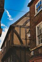 caratteristico graticcio edificio con esposto di legno travi sotto un' chiaro blu cielo, in mostra tradizionale architettonico dettagli e un' Vintage ▾ strada lampada nel York, nord yorkshire, Inghilterra. foto