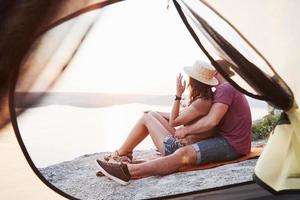 vista dalla tenda della coppia sdraiata vista lago durante l'escursione. avel lifestyle concept vacanze avventurose all'aperto foto
