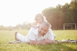 ritratto del nonno con la nipote, che si rilassano insieme nel parco foto