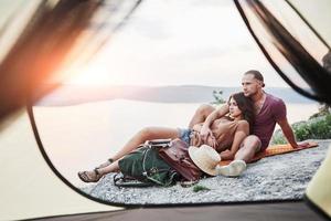 vista dalla tenda della coppia sdraiata vista lago durante l'escursione. avel lifestyle concept vacanze avventurose all'aperto foto