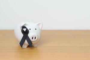 melanoma e pelle Maggio cancro mese, nero nastro con porcellino banca per supporto malattia vita. Salute, donazione, beneficenza, campagna, i soldi Salvataggio, fondo e mondo cancro giorno concetto foto