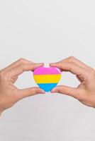 pansexual orgoglio giorno e lgbt orgoglio mese concetto. mano Tenere rosa, giallo e blu cuore forma per lesbica, gay, bisessuale, transgender, strano e pansexual Comunità foto