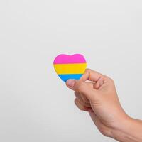 pansexual orgoglio giorno e lgbt orgoglio mese concetto. mano Tenere rosa, giallo e blu cuore forma per lesbica, gay, bisessuale, transgender, strano e pansexual Comunità foto