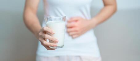 lattosio intolleranza e latte allergia concetto. donna hold latte bicchiere e avendo addominale crampi e dolore quando bevanda mucca latte. sintomo stomaco dolore, latteria intollerante, nausea, gonfiore, gas e diarrea foto