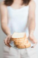 pane mangiare e quotidiano routine concetto. giovane donna mano Tenere affettato totale grano pane nel il mattina a casa foto