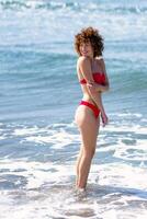 sorridente donna nel bikini in piedi nel oceano a spiaggia foto