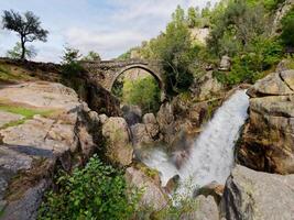 Ponte da misarela o ponte di mizarella nel montalegre, Portogallo con un' grande cascata Il prossimo per esso durante un' soleggiato giorno. rurale viaggio e vacanze nel natura. foto