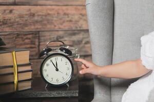 un' persona è Tenere un allarme orologio e un' pila di libri. foto