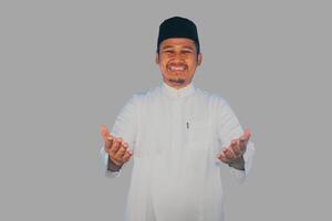 musulmano asiatico uomo sorridente amichevole fare saluto posa con braccia Aperto foto