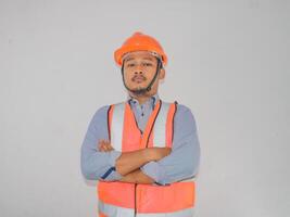 asiatico costruttore lavoratore uomo con sicurezza veste In piedi storto il suo braccio con fiducia gesto foto