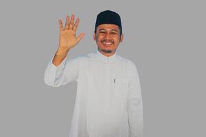 musulmano uomo a piedi e agitando mano per salutare qualcuno con contento espressione foto