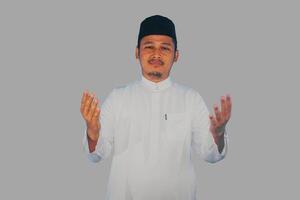 musulmano asiatico uomo sul serio preghiera a il telecamera con braccia Aperto fare preghiera gesto foto