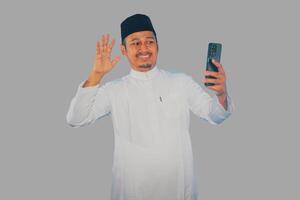 musulmano asiatico uomo mostrando eccitato viso espressione durante chiamata con il suo famiglia durante Ramadan celebrazione foto
