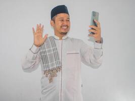 musulmano asiatico uomo mostrando eccitato viso espressione durante chiamata con il suo famiglia durante Ramadan celebrazione foto