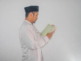 musulmano asiatico uomo sorridente a il al Corano e mentre Tenere un' al-qur'an foto