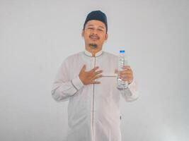 musulmano asiatico uomo mostrando sollevato espressione dopo bevanda un' acqua foto