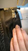 processi di cucire nel un' cucire macchina cucire donna di mani manicure nero tessile denim jeans produzione vicino su sarta nel laboratorio tessuto Abiti fabbricazione design passatempo fatto a mano Lavorando cucito foto