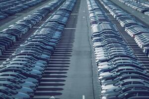 righe di un' nuovo macchine parcheggiata nel un' distribuzione centro su un' auto fabbrica su un' soleggiato giorno. superiore Visualizza per il parcheggio. foto