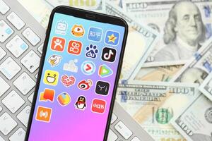 kiev, Ucraina - aprile 1, 2024 asiatico applicazioni icona su smartphone schermo su molti Dollaro statunitense i soldi fatture foto