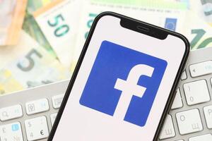 kiev, Ucraina - aprile 1, 2024 Facebook icona su smartphone schermo su molti Euro i soldi fatture foto