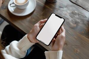 mani Tenere Telefono con bianca modello schermo contro caffè tavolo fondale foto