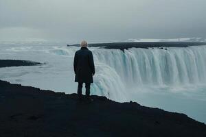 uomo in piedi su il bordo di un' cascata guardare a il oceano foto