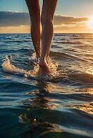 un' persona a piedi nel il oceano a tramonto foto