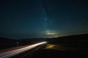 il notte cielo al di sopra di un' città e montagne foto