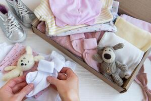 Da donna mani raccogliere figli di Abiti in scatole. foto