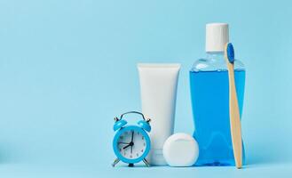 collutorio e dentifricio tubo, allarme orologio su blu sfondo foto