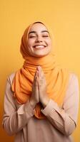 europeo donna indossare sciarpa è preghiere e sorridente su arancia sfondo foto
