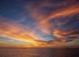 tramonto al di sopra di il oceano con nuvole e montagne nel il sfondo foto
