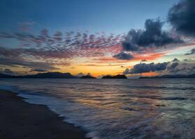 tramonto al di sopra di il oceano con nuvole e montagne nel il sfondo foto