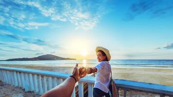 gli amanti asiatici felici e sorridi tenendosi per mano. viaggio in spiaggia per le vacanze estive. foto