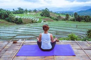 donna asiatica rilassarsi in vacanza. gioca se lo yoga. sul balcone paesaggio campo naturale foto