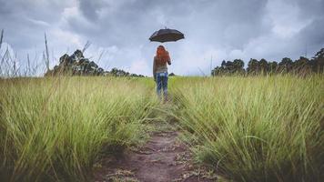 donne in piedi ombrello sul prato verde nella stagione delle piogge. donne asiatiche foto