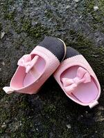 carino poco bambino scarpe rosa e nero colore su gesso e muschio impianti sfondo foto