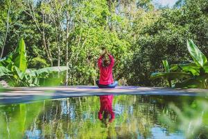 le donne asiatiche si rilassano durante le vacanze. gioca se yoga in piscina. giovane donna viaggio natura lei in piedi esercizio. foto