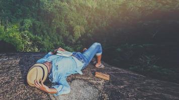 il viaggio dell'uomo asiatico si rilassa durante le vacanze. dormire rilassarsi leggere libri su scogliere rocciose. sulla montagna. in Thailandia
