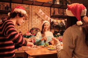 gli amici si divertono a cenare a tavola con cibi speciali, come tacchino arrosto e vino nella sala da pranzo di casa, decorata con ornamenti, festa di Natale e festa di Capodanno. foto