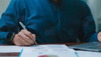 uomo d'affari è scrittura su un' pezzo di carta con un' penna. concetto di messa a fuoco e concentrazione come il uomo accuratamente scrive. il blu camicia lui è indossare Aggiunge un' toccare di professionalità per il scena foto