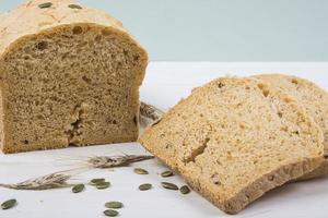 pane rustico con lievito di grano con semi di zucca su fondo di legno bianco foto